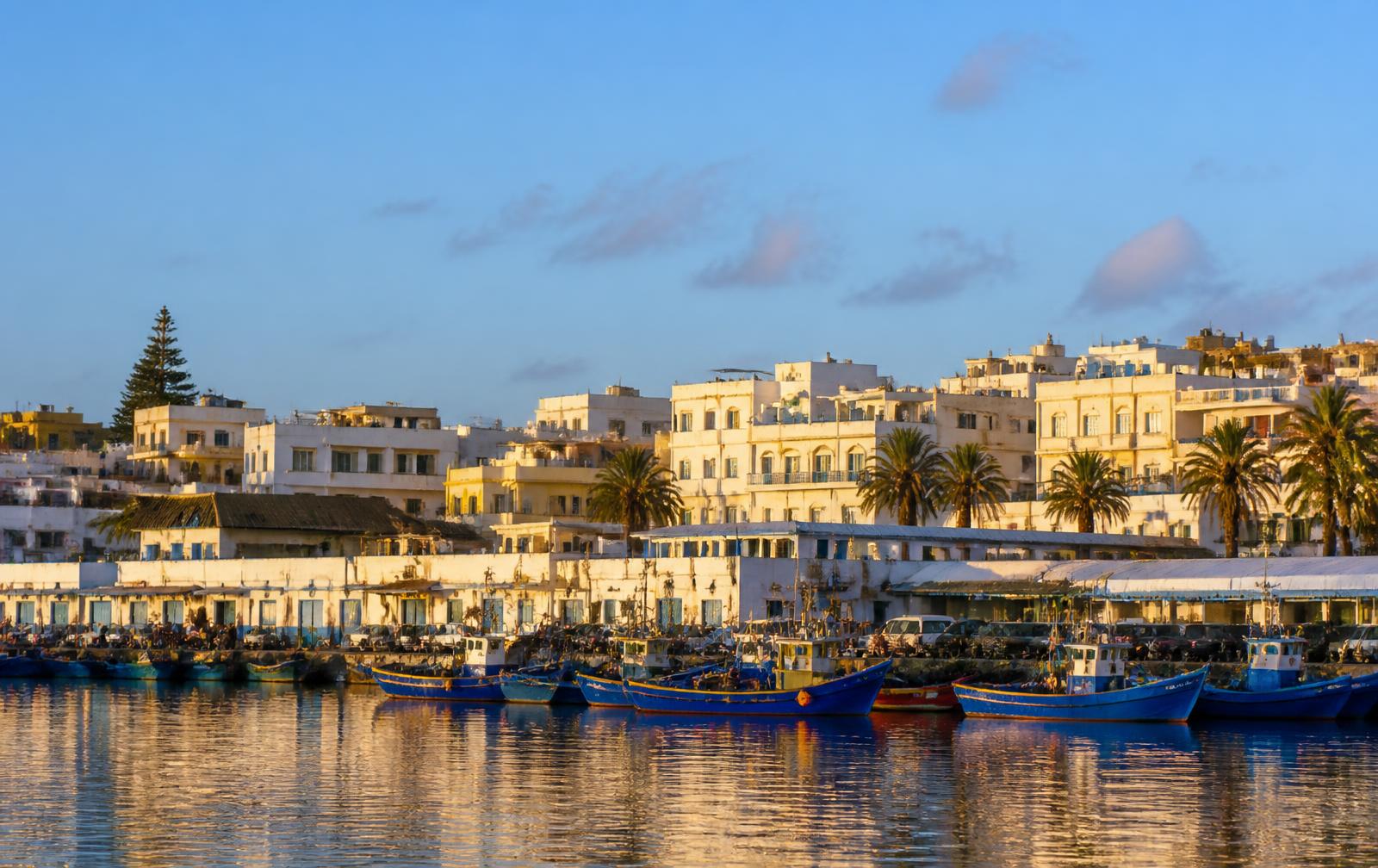 Port de Larache avec bateaux de pêche et façades blanches au coucher du soleil